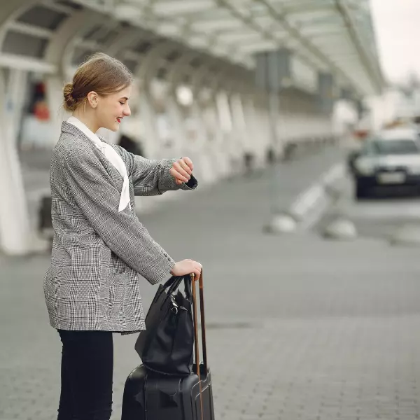 Mujer mirando su reloj con una maleta de viajes esperando en el aeropuerto