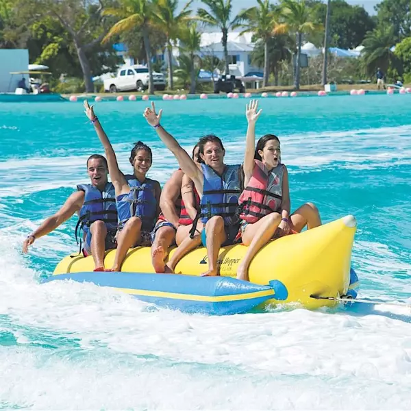 Cinco personas adolescentes y niños sobre una banana acuática en el lago artificial de Playa Blanca Panamá