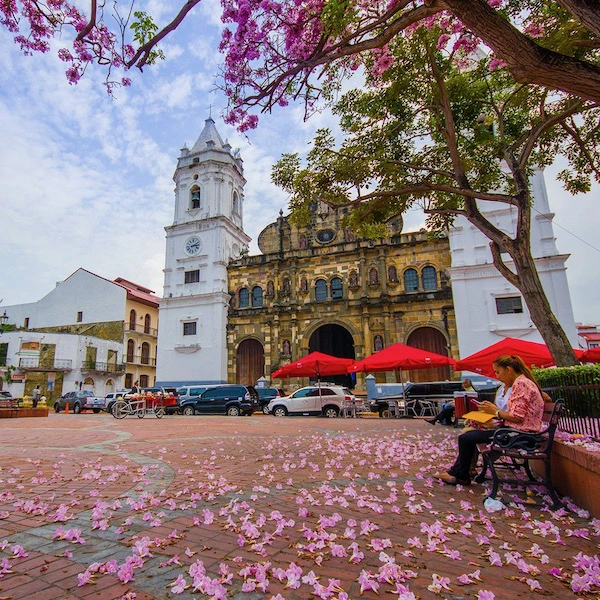 Catedral del Casco Antiguo de Panamá desde la plaza con una señora sentada leyendo en un banco de la plaza