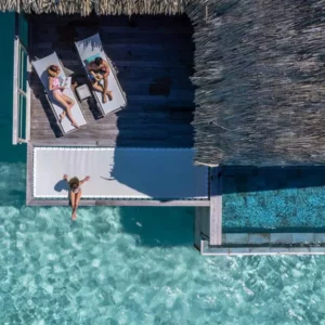 Una pareja en reposera sobre la terraza de su cabaña sobre el mar en Bora Bora Polinesia