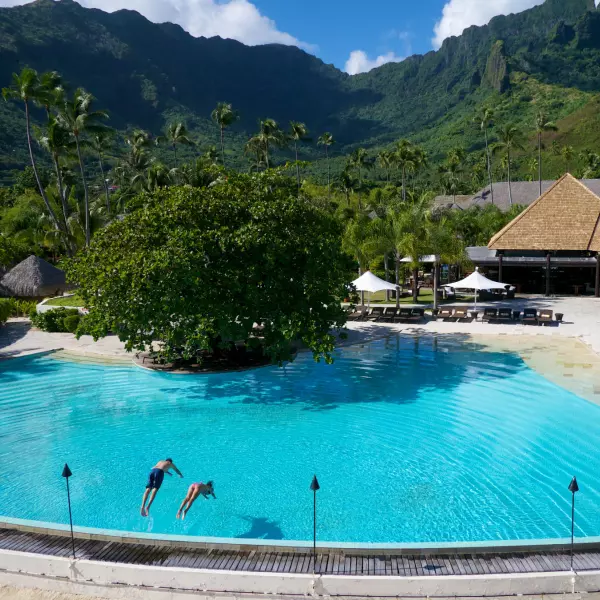 Una pareja arrojándose a uns inmensa piscina en el hotel de Polinesia Francesa