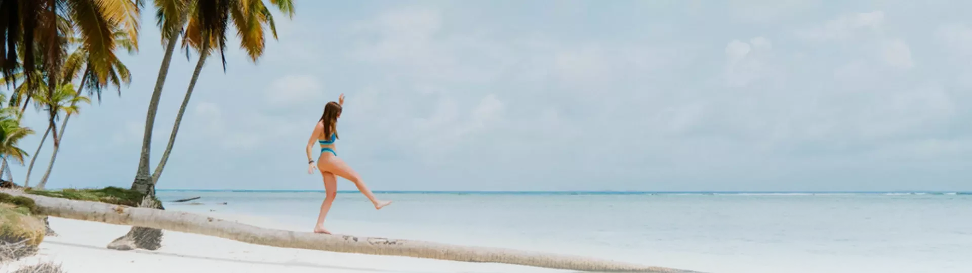 Mujer caminando en un tronco caído a orillas del mar sobre la playa de Panamá
